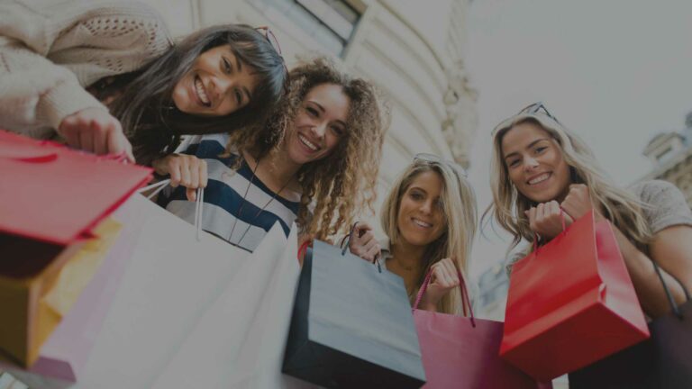 Quatro mulheres felizes com sacolas de compras na mão